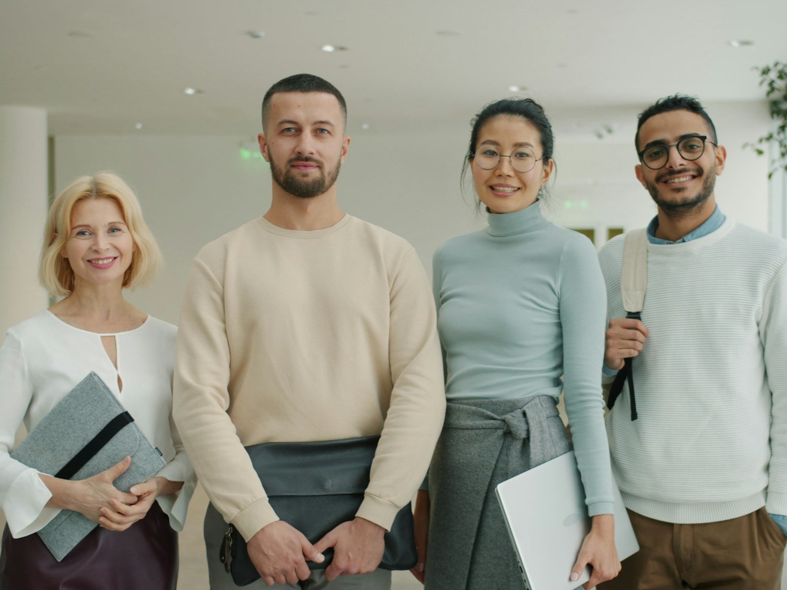 Four smiling colleagues standing together in a bright lobby