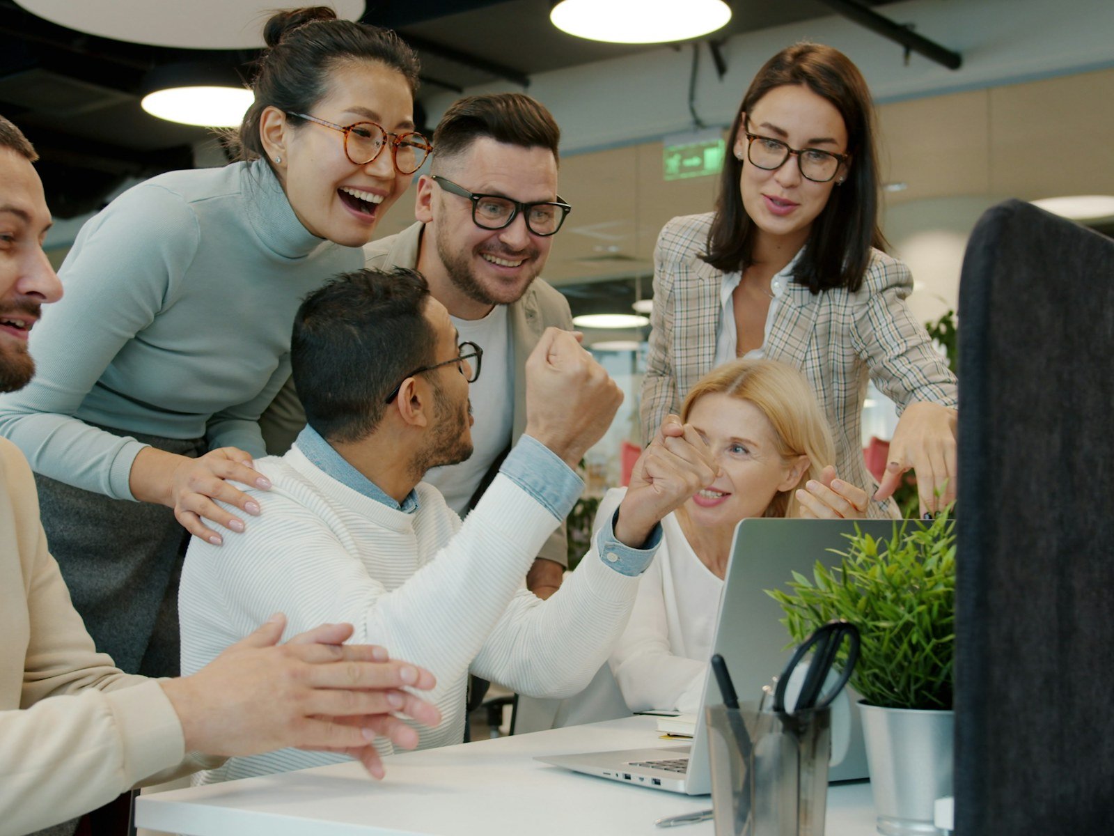 A diverse team celebrating good news together around a laptop