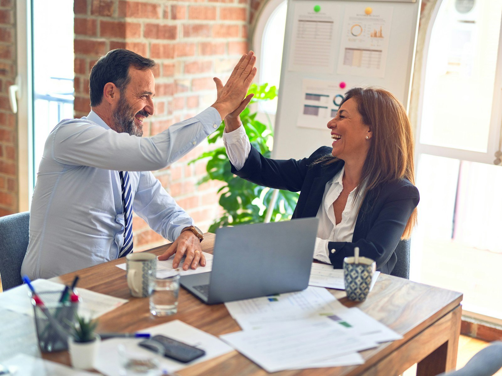 Two colleagues sharing a high five at a table