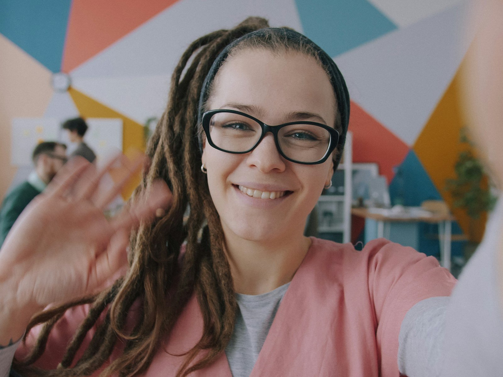 A smiling woman waving hello to welcome a new colleague