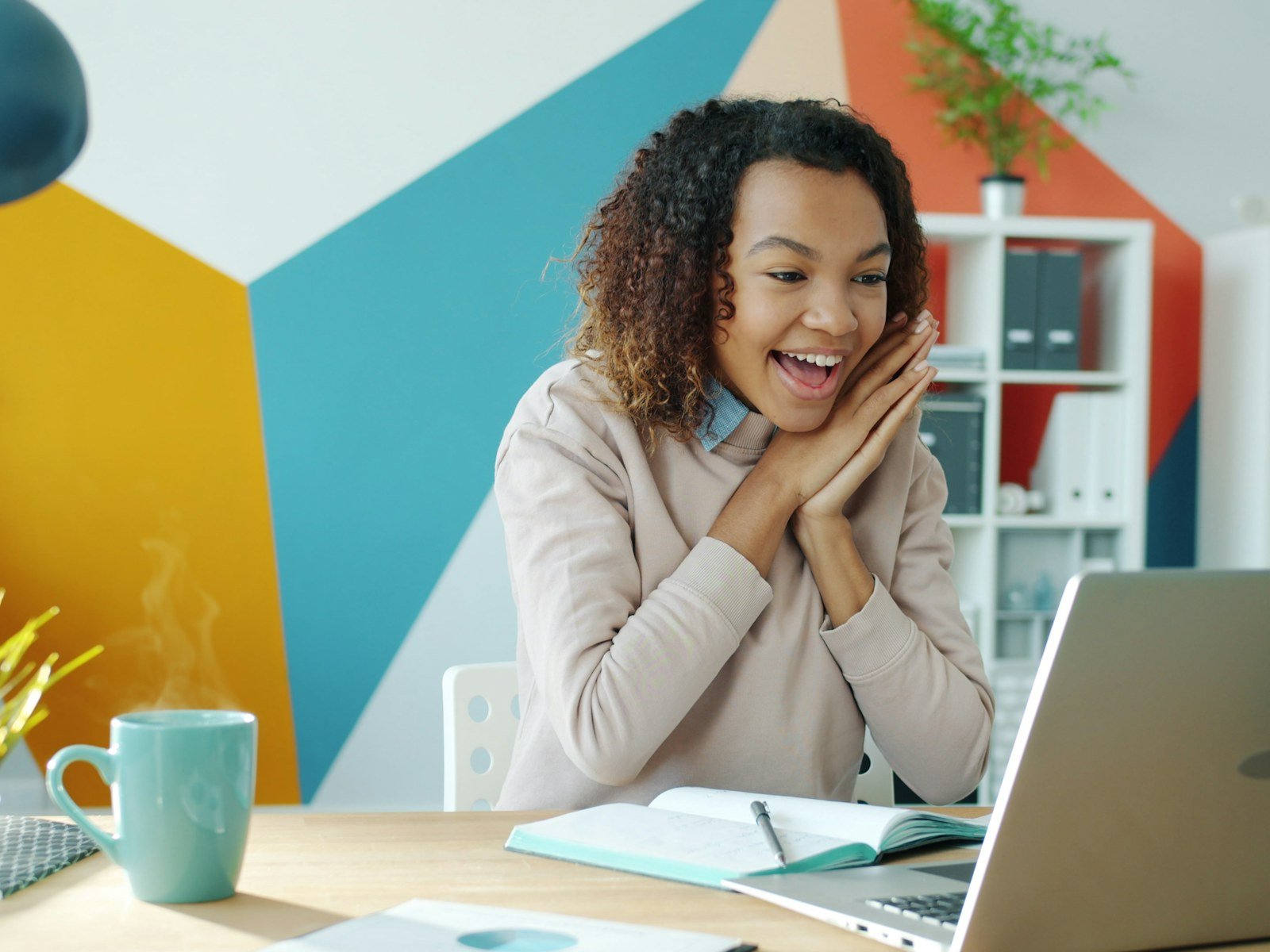 A delighted woman reacting to good news on her laptop