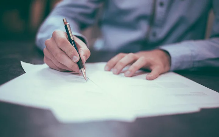 Hand signing a document with a pen