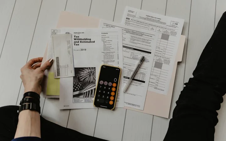 Calculator, pen and tax forms on a desk