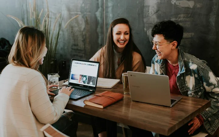Team members sharing laptops at a table