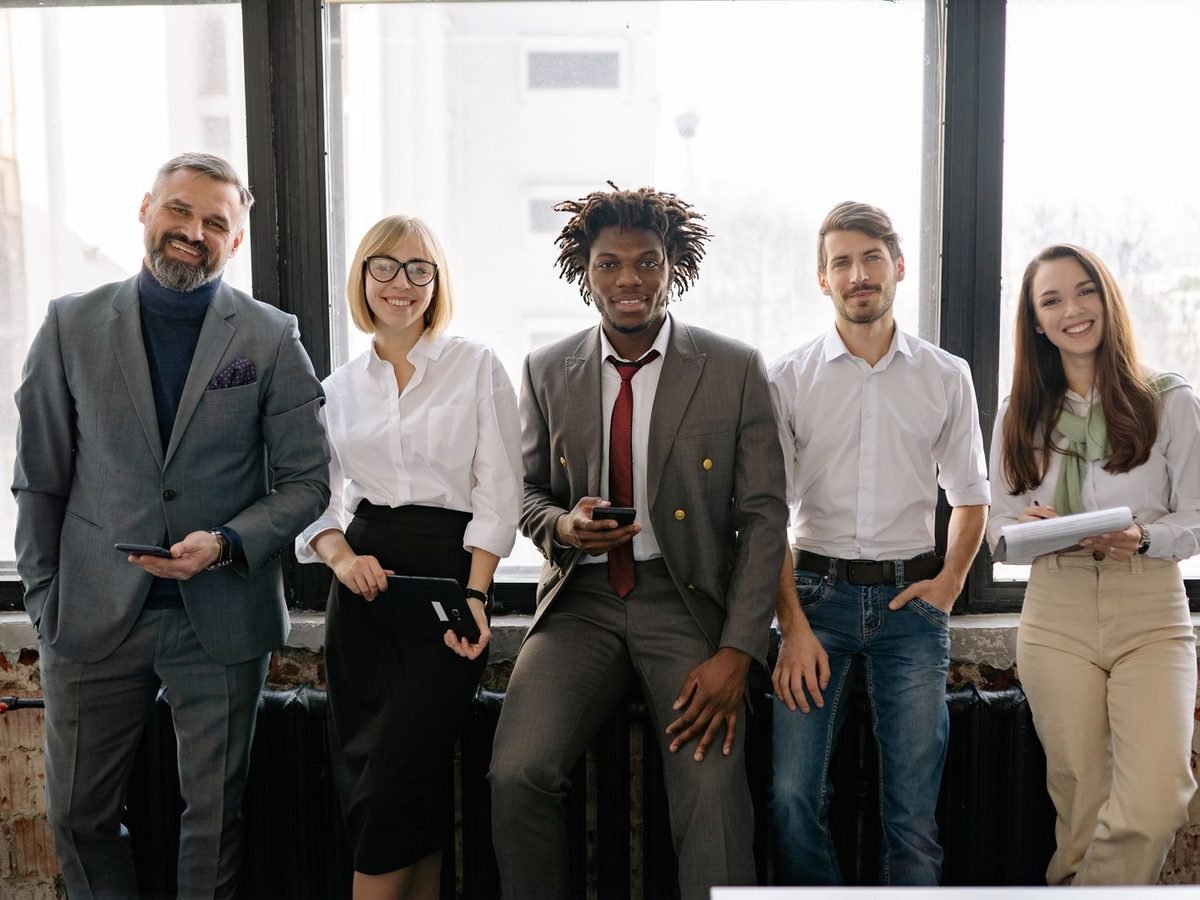 Diverse group of smiling professionals standing together by office windows