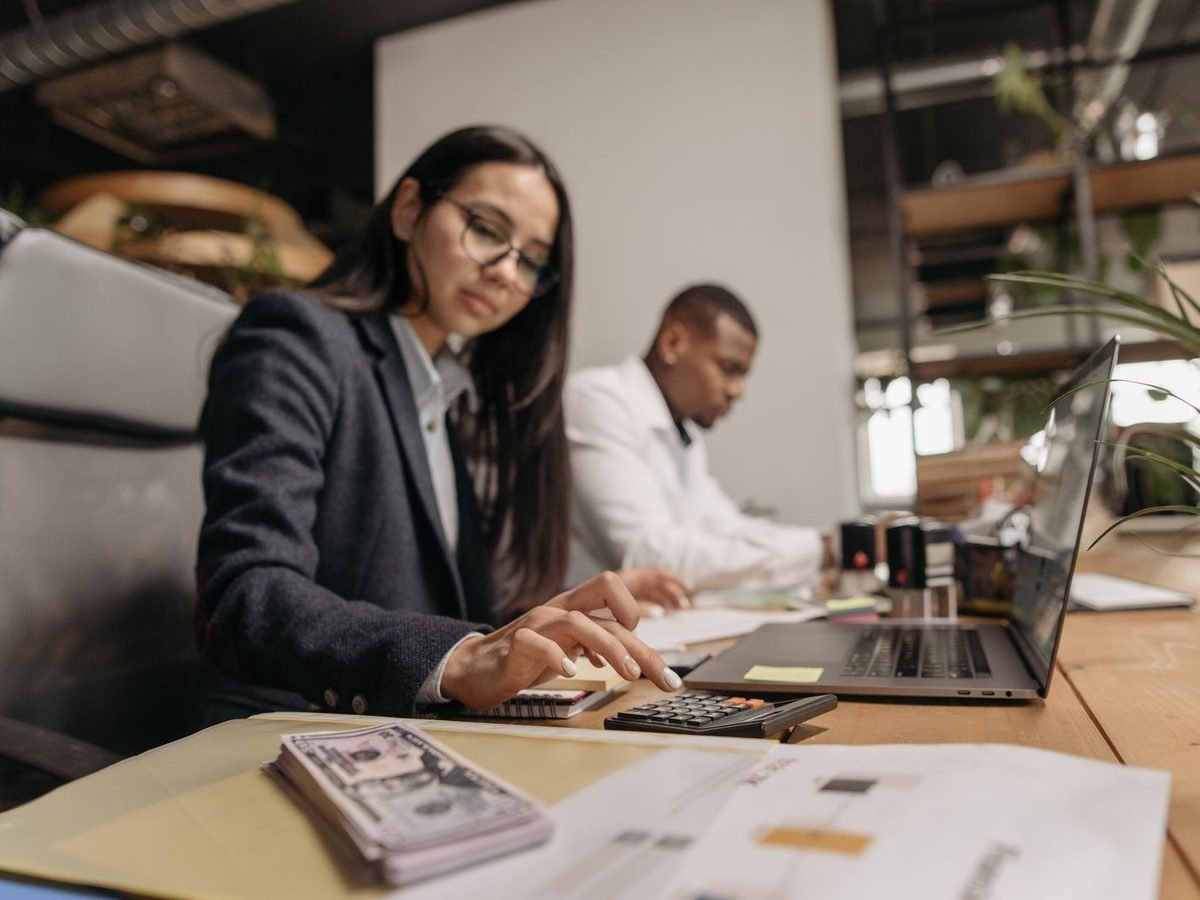 Two finance colleagues working with a laptop and calculator