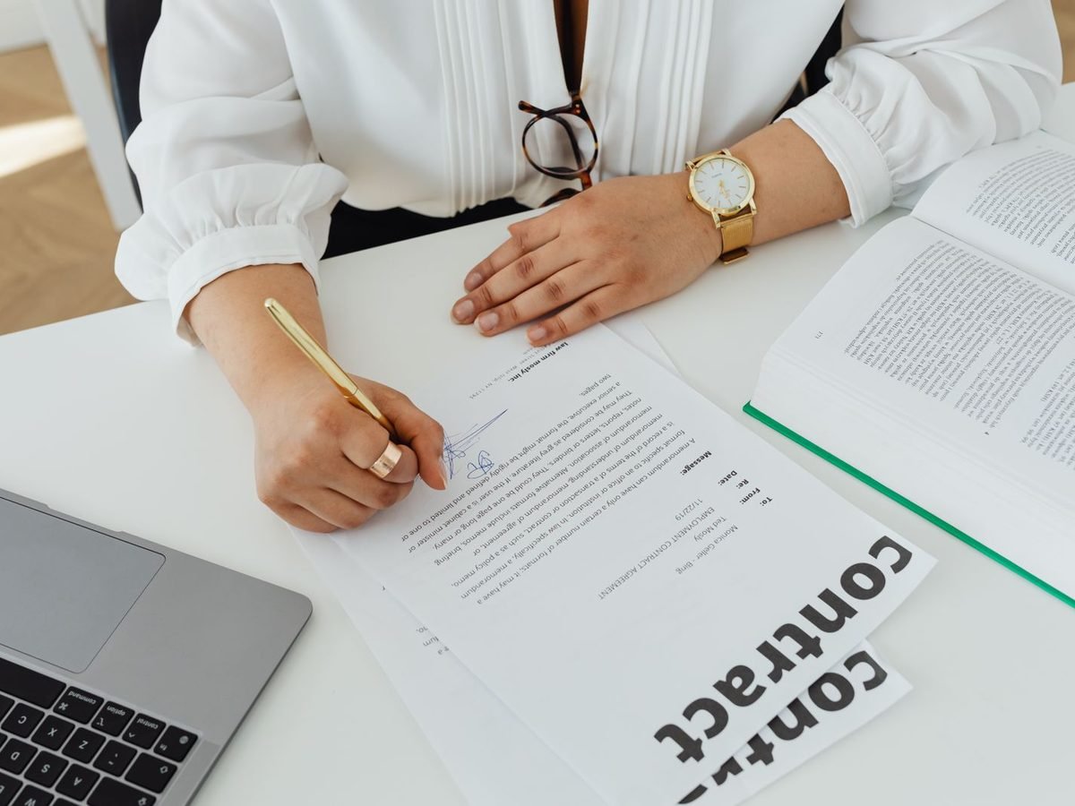 Professional reviewing a contract at a white desk with a laptop