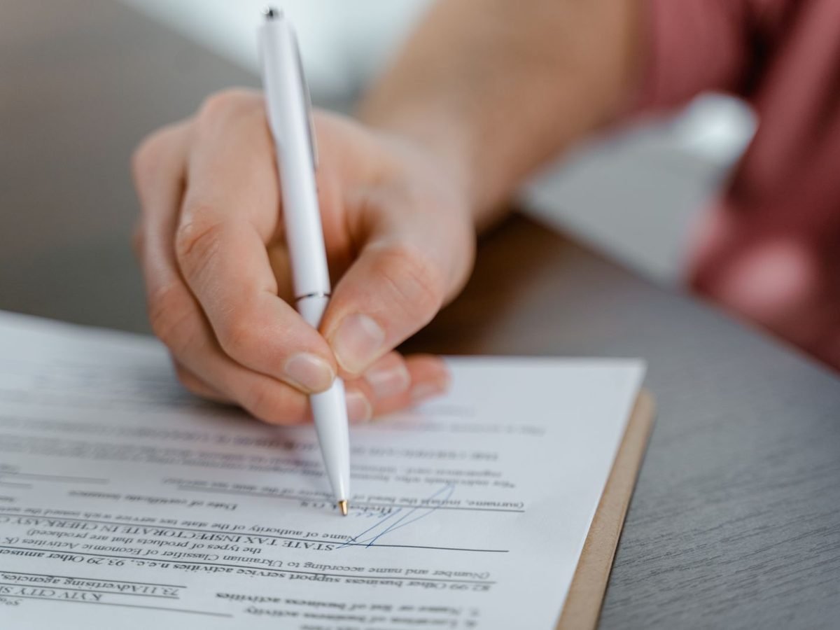 Hand signing a document with a pen
