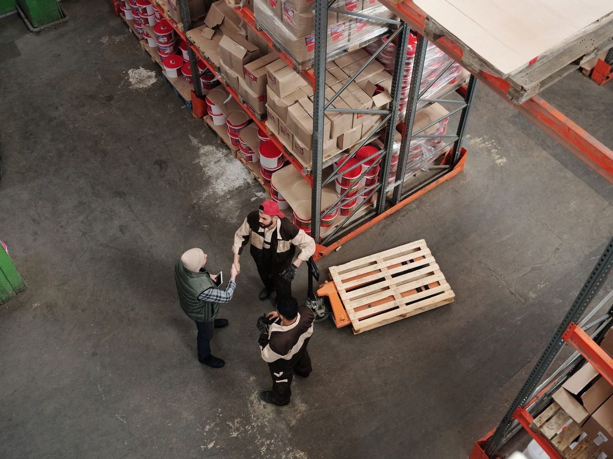 Workers discussing logistics in a warehouse seen from above