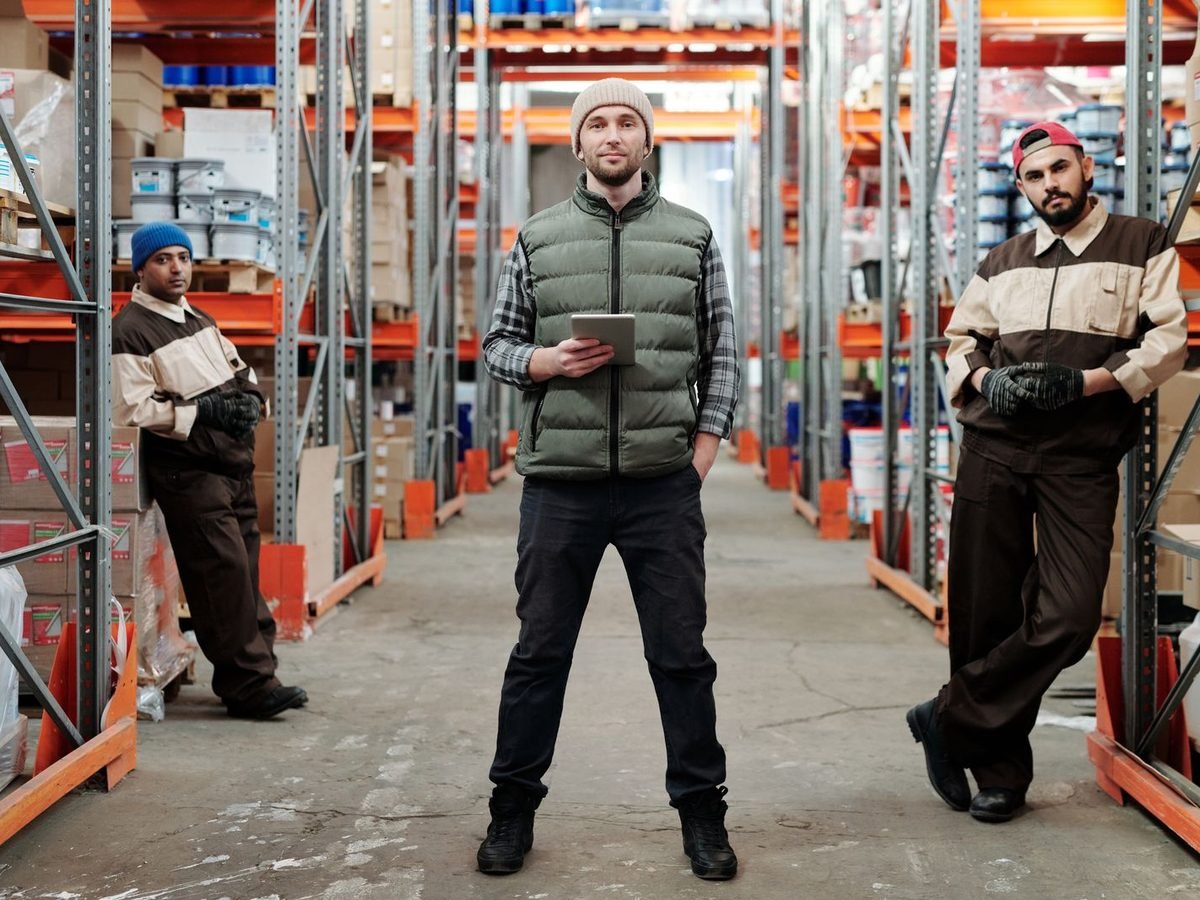 Three warehouse team members standing in a stocked aisle